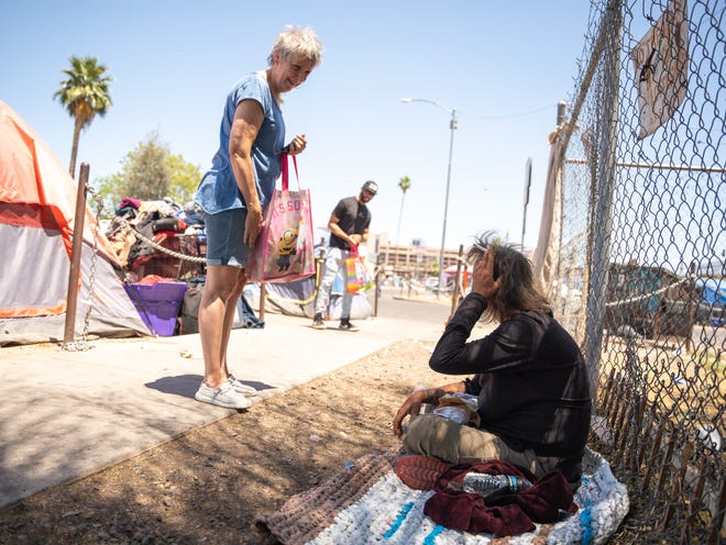 Katie Oswald hands out sandwiches in the homeless encampment known as "The Zone" in Phoenix on May 8, 2023. Oswald hands out The Old Station Subs sandwiches with thoughts of her son who had lived in "The Zone."