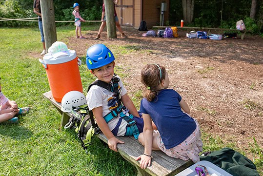 two children sitting on a bench outside during camp