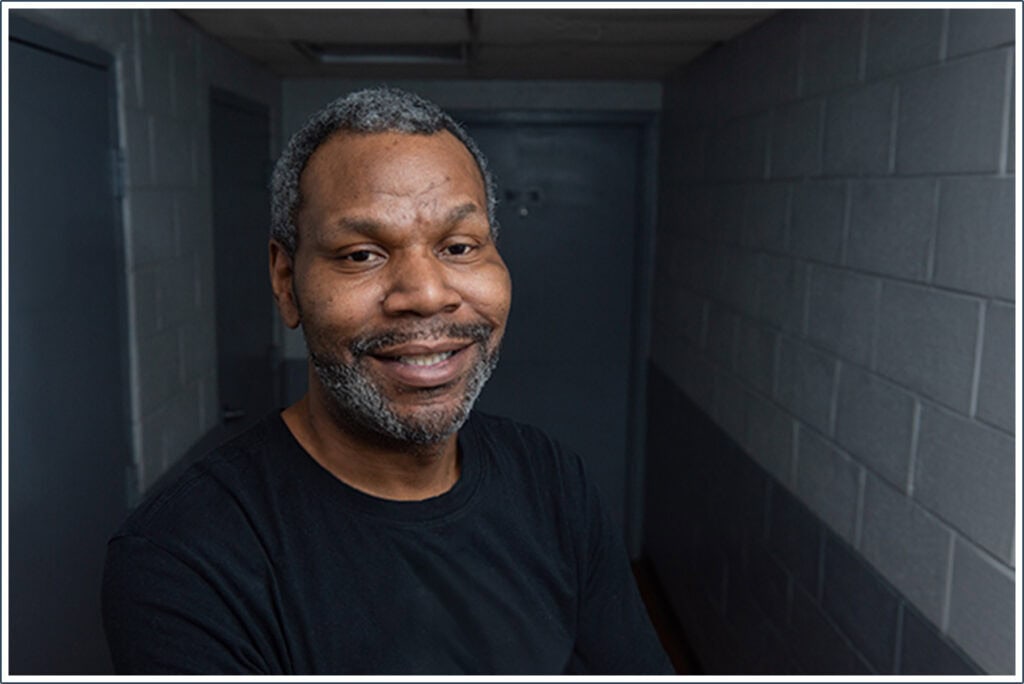 African American Man, Jamie standing in dark hallway